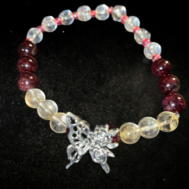 ENERGIE DE VIE Bracelet en perles transparentes et rouges avec un pendentif en forme de papillon.